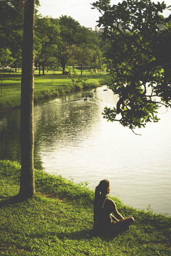 Femme en méditation dans la nature au bord de l'eau avec une pierre